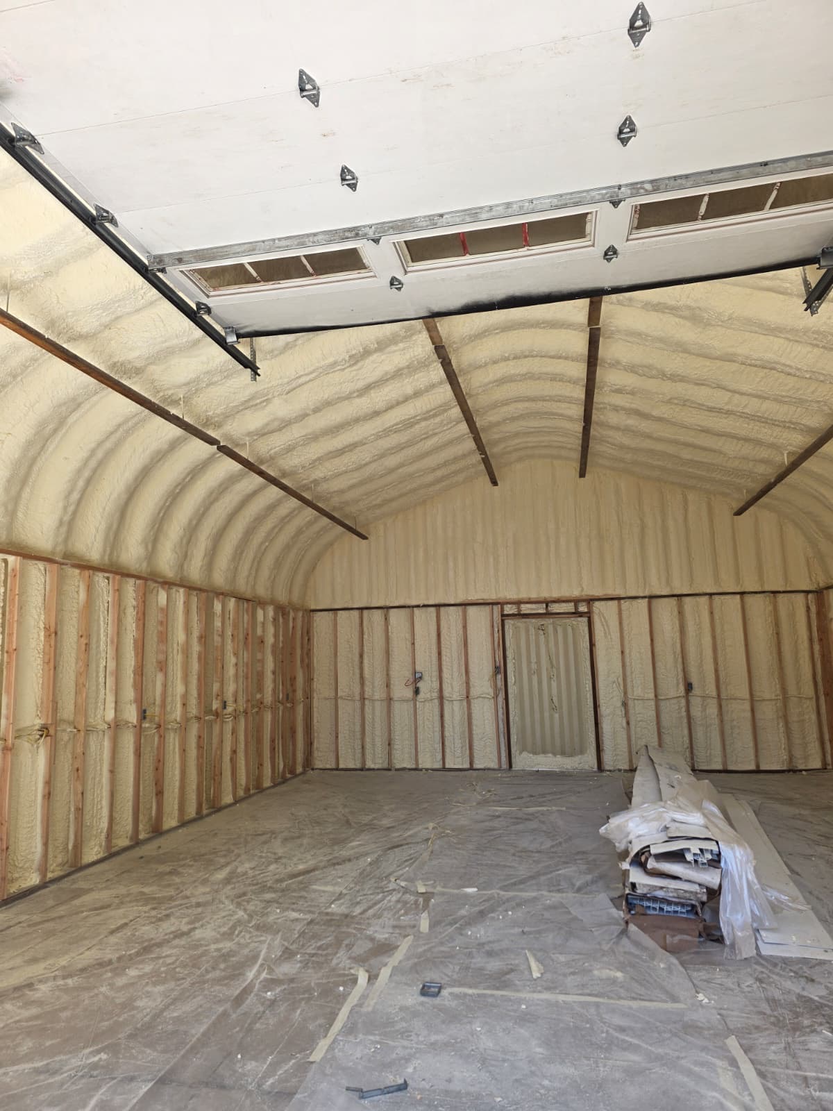 Arched metal building interior with complete spray foam insulation coverage — Pacific Northwest
